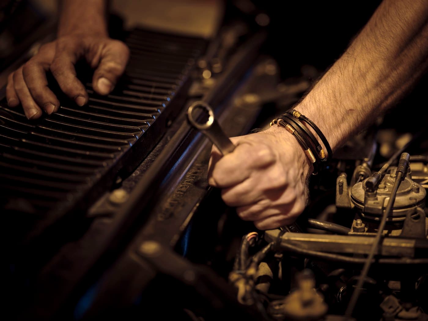 Mechanic tightening a part in an engine bay with a wrench