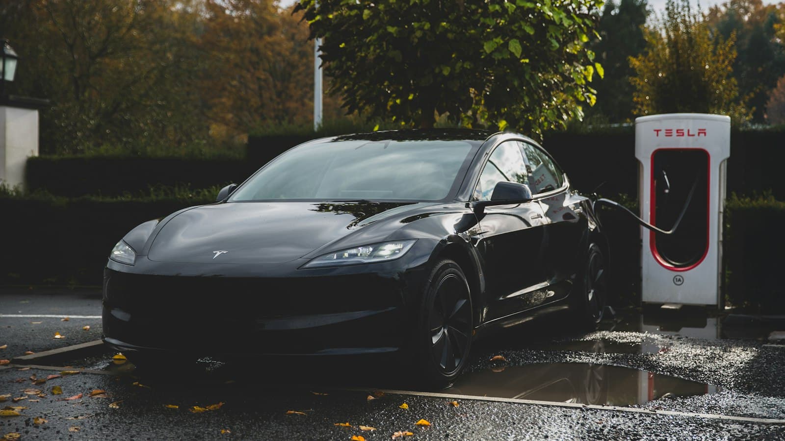 Black Tesla Model 3 plugged into a charging station