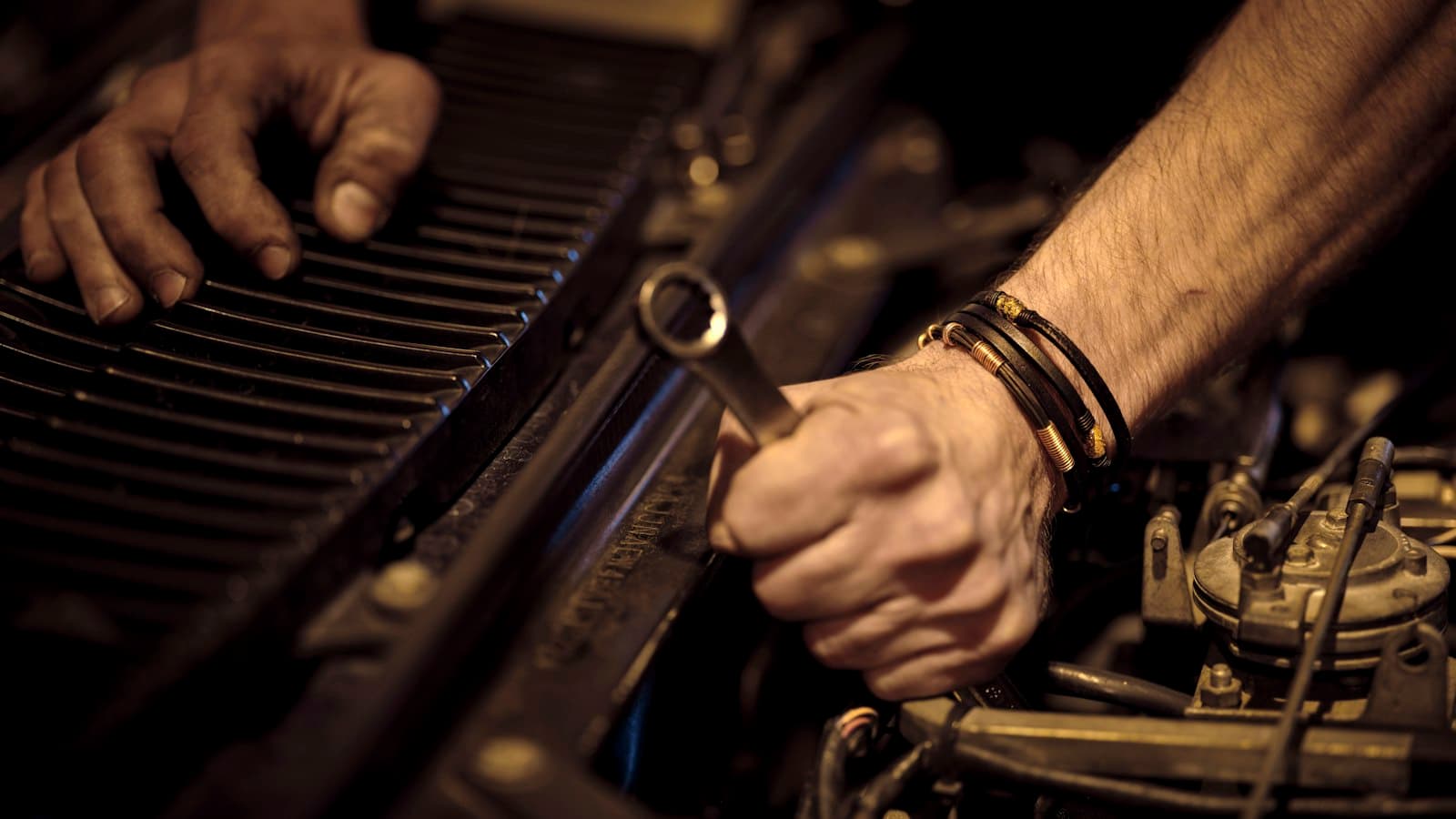 Technician tightening a bolt in an engine bay with a wrench